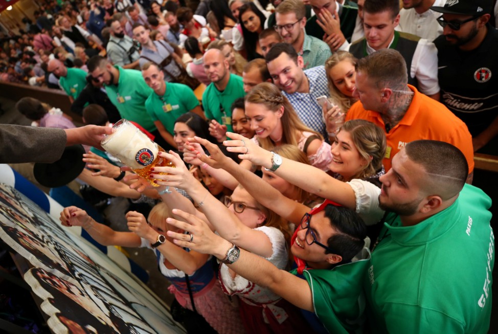 Visitors reach for the first mugs of beer during the opening day of the 185th Oktoberfest in Munich