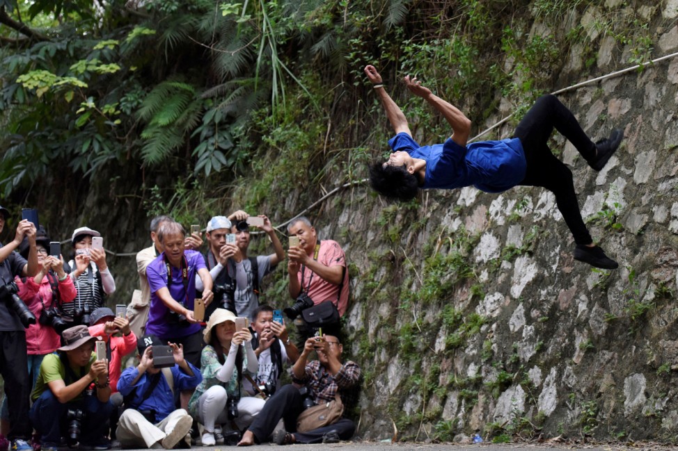 Onlookers take pictures of a man performing parkour in Nanning