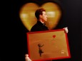 FILE PHOTO: An employee walks with artist Banksy's 'Girl and Balloon' 2009 signed and inscribed For Mike, past artist  Ryan Callanan's (known as RYCA) 'Mega Heart' 2011 at Bonhams auction house in London