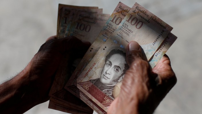 A man counts Venezuelan bolivar notes in downtown Caracas