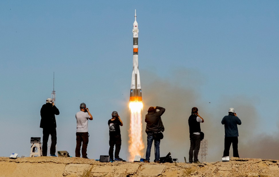 Photographers take pictures as the Soyuz MS-10 spacecraft carrying the crew of astronaut Nick Hague of the U.S. and cosmonaut Alexey Ovchinin of Russia blasts off to the International Space Station (ISS) from the launchpad at the Baikonur Cosmodrome