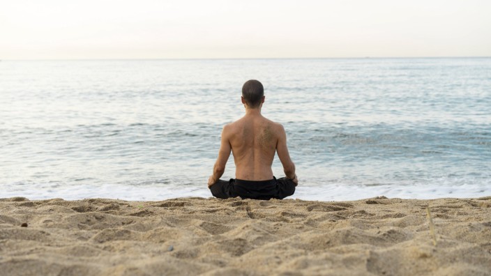 Spain Man doing yoga on the beach in the evening meditation rear view model released Symbolfoto P