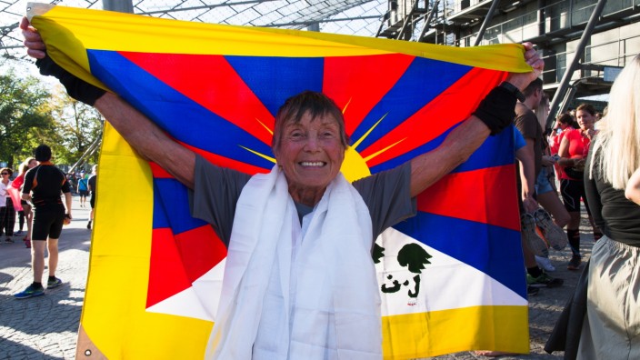 München Marathon: Dauerläuferin mit Mission: Sigrid Eichner, 78, jubelt nach dem Zieleinlauf im Münchner Olympiapark mit der Flagge Tibets.