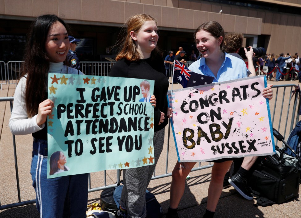 Girls hold posters during a visit by Britain's Prince Harry and wife Meghan, Duchess of Sussex at the Sydney Opera House in Sydney