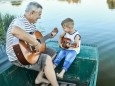 Grandfather teaching grandson playing guitar model released Symbolfoto PUBLICATIONxINxGERxSUIxAUTxH