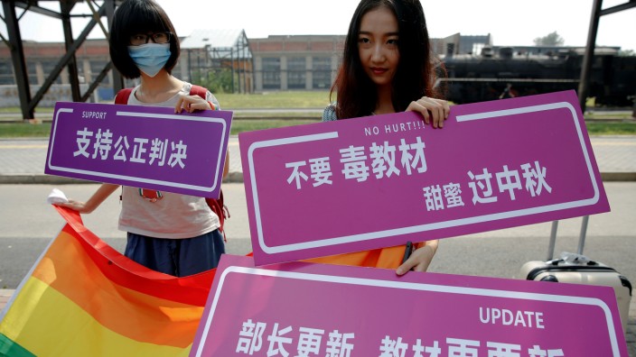 Supporters hold a rainbow flag and signs near the courthouse before the hearing in which a Chinese student lodged a suit against the Ministry of Education over school textbooks describing homosexuality as a mental disorder, in Beijing