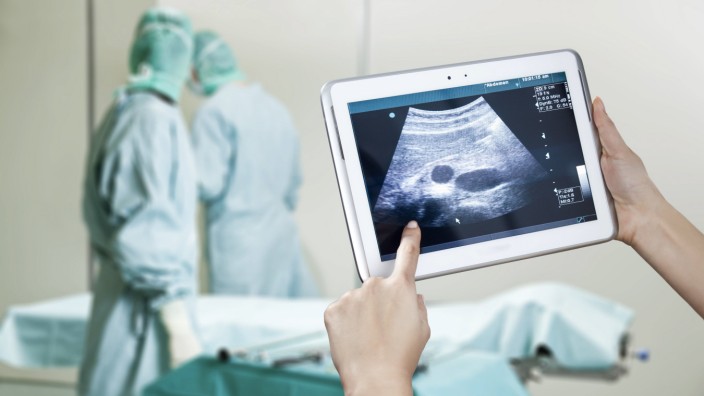 Hands holding digital tablet with ultrasound image in operating theatre model released Symbolfoto PU
