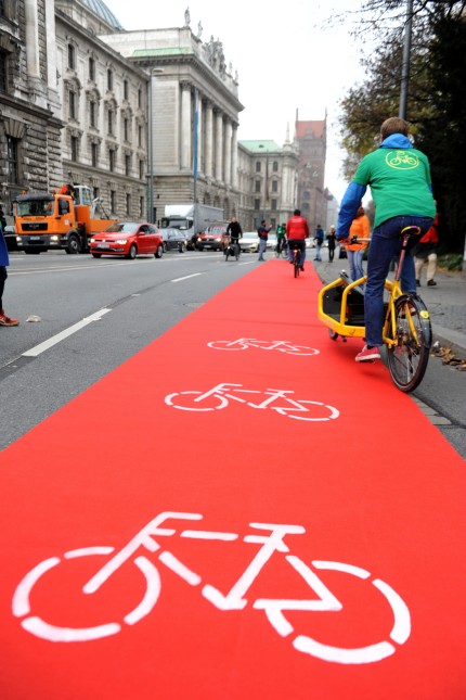 Stadtverkehr: Aktivisten entrollen einen roten Teppich auf der Elisenstraße, mit dem sie sichere Fahrspuren für Radler fordern.