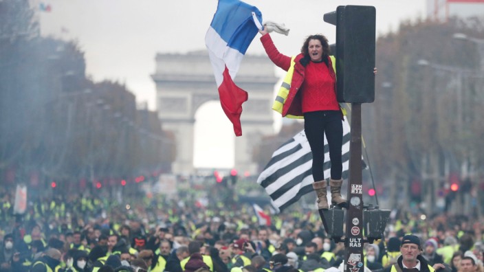 A protester wearing yellow vest, a symbol of a French drivers' protest against higher fuel prices, stands on the red light on the Champs-Elysee in Paris