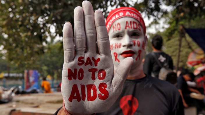 A man poses as he displays his hand and face painted with messages during an HIV/AIDS awareness campaign on the eve of World AIDS Day in Kolkata