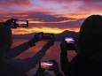 Menschen fotografieren den Sonnenuntergang mit ihrem Smartphone bei Luino Lago Maggiore Lombardei