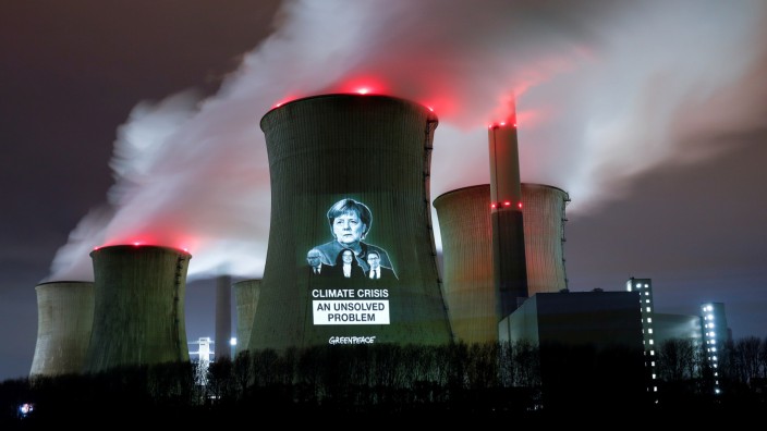 Greenpeace activists project images of German politicians with a slogan onto a cooling tower of the brown coal power plant of RWE, in Neurath