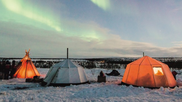 Arktis: Unter den Zelten der gefrorene Boden, darüber der Himmel mit flackernden Nordlichtern.