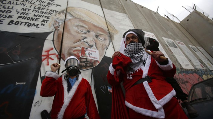 Weihnachten: Als Nikolaus verkleidete Palästinenser vor einem Graffiti, das den US-Präsidenten Trump zeigt.