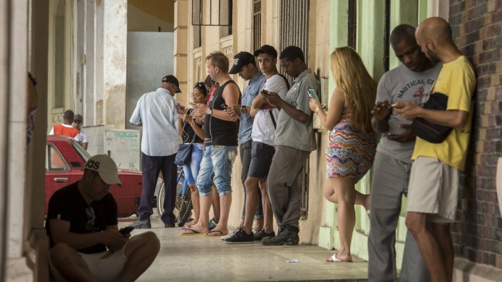 Viele Menschen telefonieren mit dem Handy am Hotspot der Uferpromenade Malecon Kuba *** Many peopl