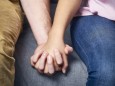 Partial view of couple holding hands on couch PUBLICATIONxINxGERxSUIxAUTxHUNxONLY DISF002262