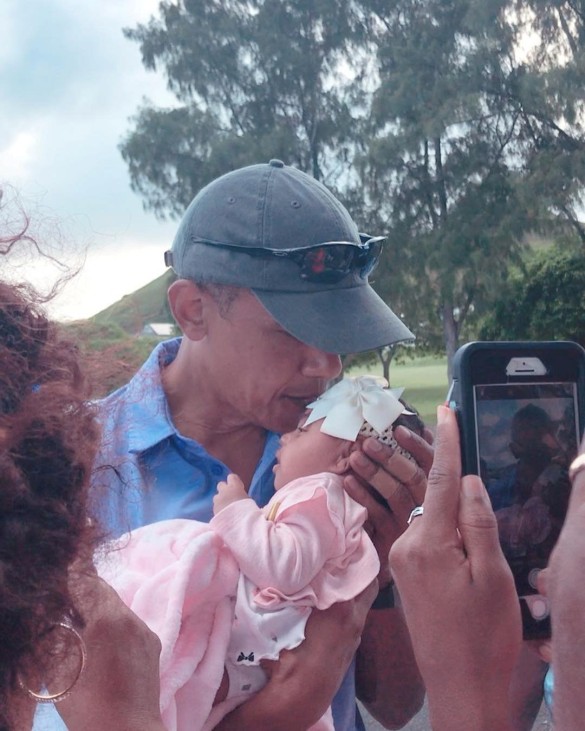 Former U.S. President Barack Obama kisses a baby during a visit to Kailua