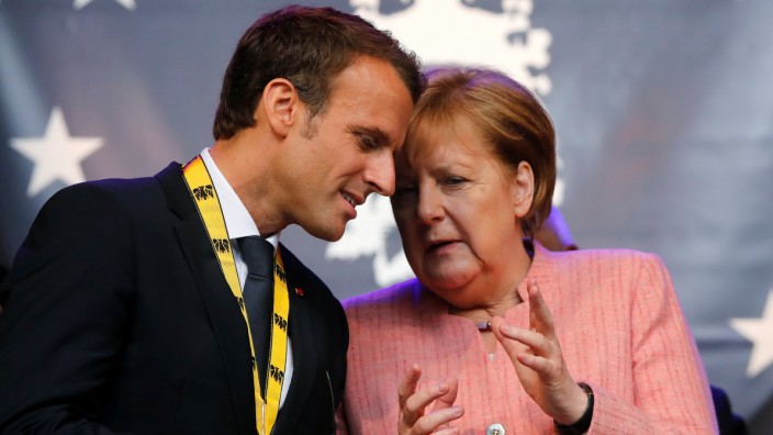 FILE PHOTO: French President Emmanuel Macron speaks with German Chancellor Angela Merkel after being awarded the Charlemagne Prize for 'European vision' in Aachen, Germany
