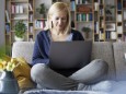 Woman at home sitting on couch using laptop model released Symbolfoto property released PUBLICATIONx