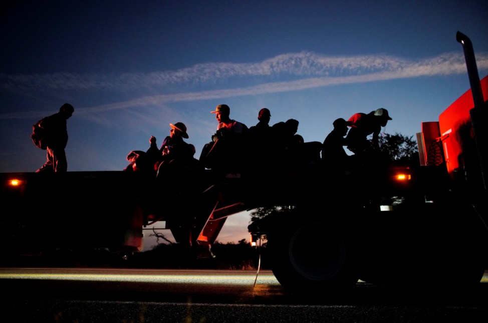 Migrants take a lift in the back of a truck during their journey towards the United States, in Chauites, Mexico