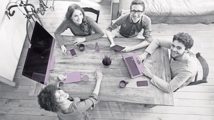 Elevated view of smiling coworkers working together at wooden table in office model released Symbolf