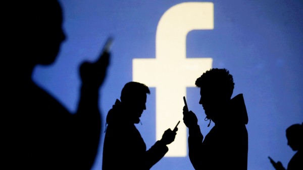 Facebook - Smartphone-Nutzer stehen vor dem Facebook-Logo