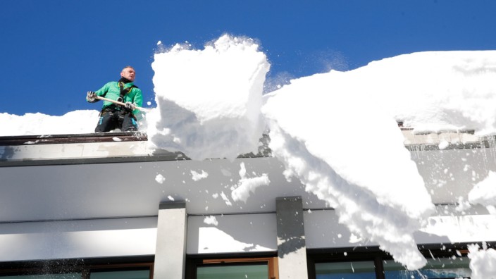 A worker removes snow from the roof of a building in Davos