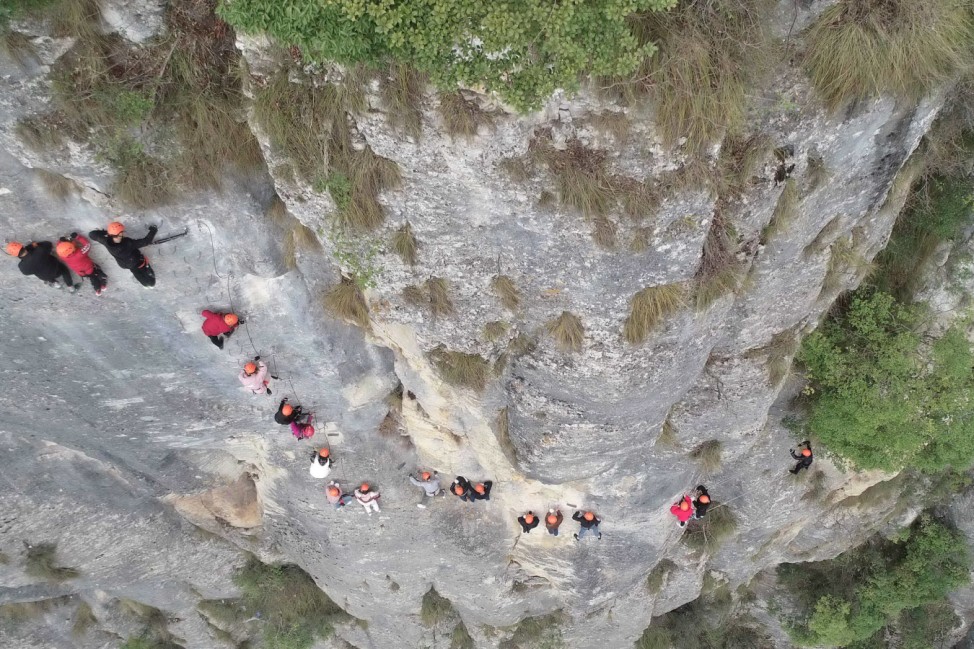 Touristen klettern eine Felswand hoch
