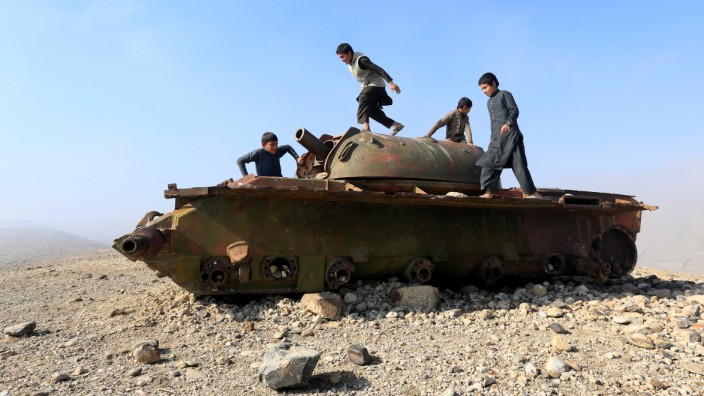 Afghan children play on the remains of a Soviet-era tank on the outskirts of Jalalabad,