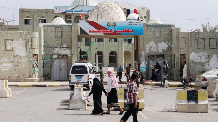 People walk past the headquarters of municipality of the Red Sea port city of Hodeidah, Yemen