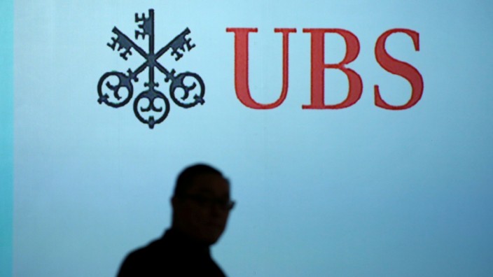 FILE PHOTO: A man walks past a UBS logo projected on a screen in Singapore