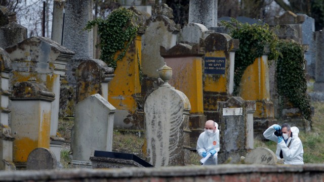 French gendarmes conduct their investigation as they examine graves that were desecrated with swastikas in the Jewish cemetery in Quatzenheim