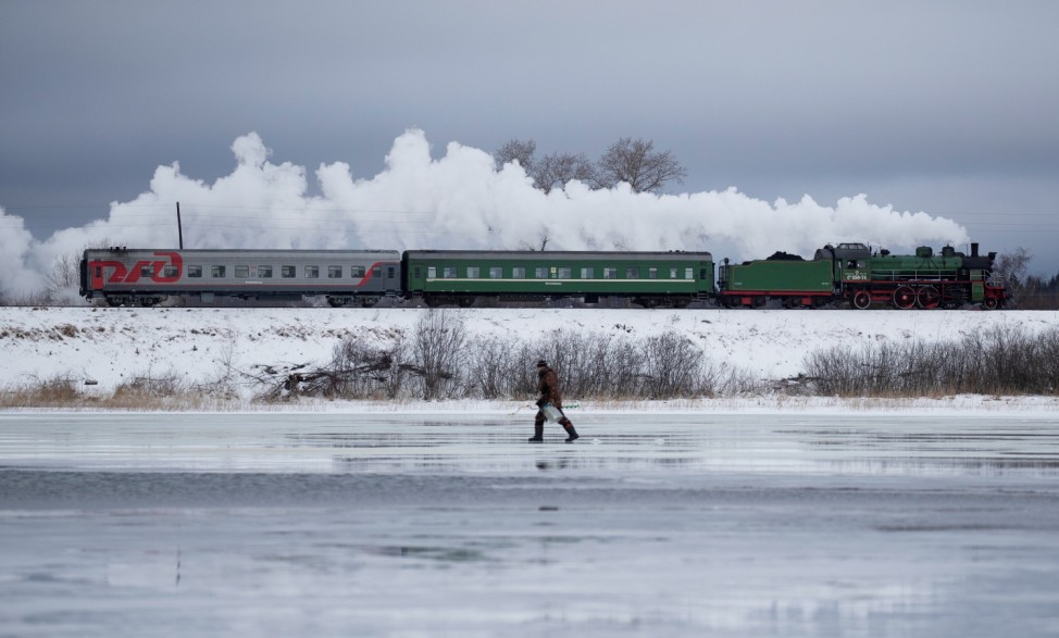 A steam train passes by along a dam outside Ostashkov