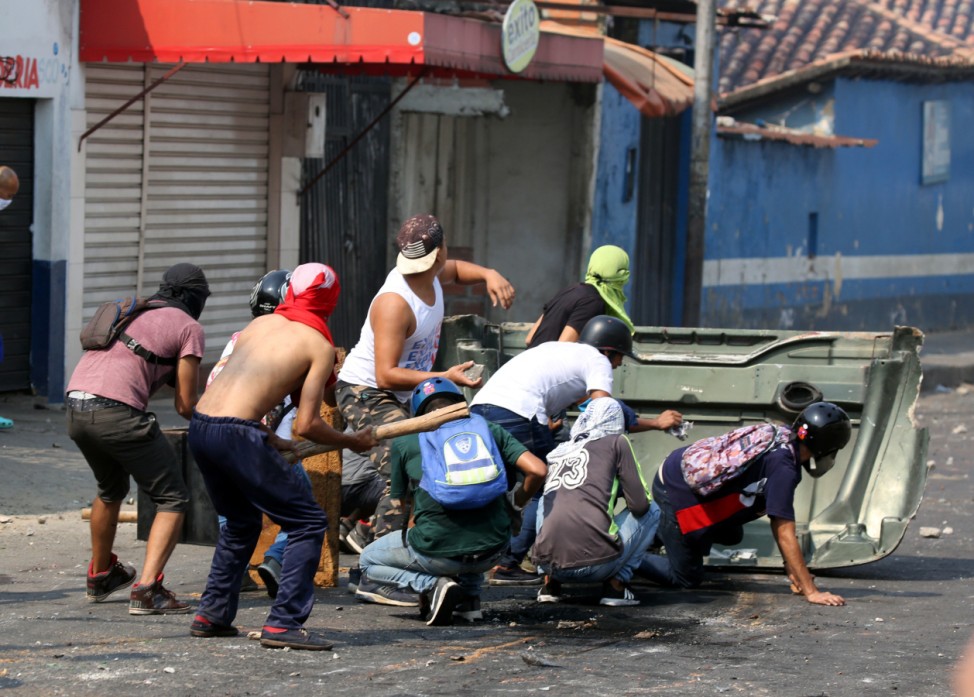 Demonstrators take cover while clashing with security forces in Urena