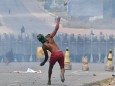 Venezuela - Ein Demonstrant wirft Steine in Richtung der Nationalgarde