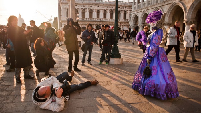 Ein Tourist fotografiert eine maskierte Frau beim Karneval in Venedig.