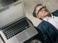 Mature businessman lying on carpet next to laptop model released Symbolfoto property released PUBLIC