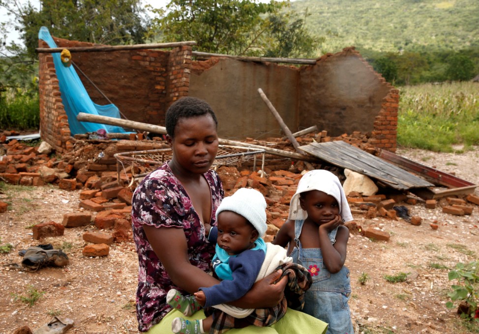 Nomatter Ncube and her kids sit beside their washed away family home following Cyclone Idai in Chimanimani district