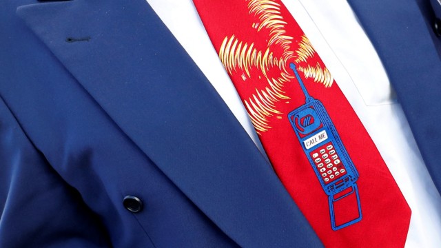 An employee of Germany's Federal Network Agency (Bundesnetzagentur) sports a tie showing a mobile phone reading 'call me' prior to the auction of spectrum for 5G services at the Bundesnetzagentur head quarters in Mainz