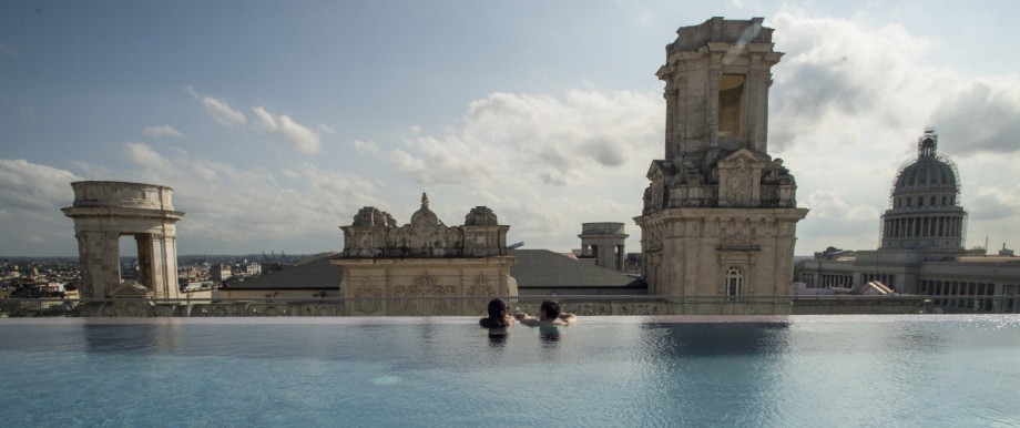Ein junges Paar schaut vom Pool der Dachterrasse eines Luxushotels auf die Altstadt von Havanna.