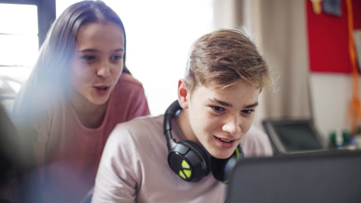 Teenage girl watching boy using laptop model released Symbolfoto property released PUBLICATIONxINxGE
