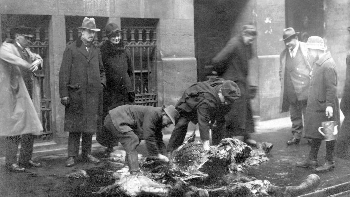 Mai 1919: Vor einem Warenhaus am Hauptbahnhof zerlegen Passanten ein erschossenes Artilleriepferd auf offener Straße.