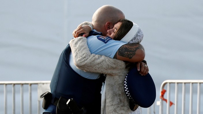 A relative of a victim of the mosque attacks hugs a policeman during a mass burial at Memorial Park Cemetery in Christchurch