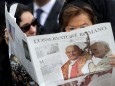 FILE PHOTO: A woman reads a copy of the Vatican newspaper L'Osservatore Romano as she waits for the canonisation ceremony in St Peter's Square at the Vatican
