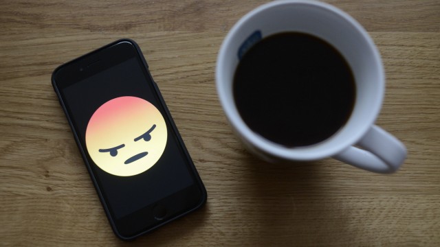 A Facebook angry face is seen on an iphone in this photo illustration iPhone and cup of coffee on a