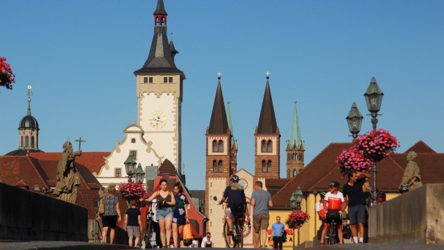 Personen auf der Alte n Mainbrücke mit dem Türmen des Rathaus es und Dom s in der Altstadt Würzburg
