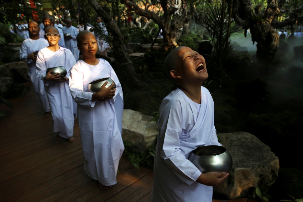 Novice nuns walk in line to receive food from people during the Songkran Festival at the Sathira-Dhammasathan Buddhist meditation centre in Bangkok