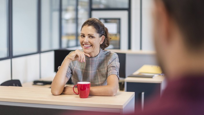 Female employee sitting at desk talking to colleague model released Symbolfoto property released PU