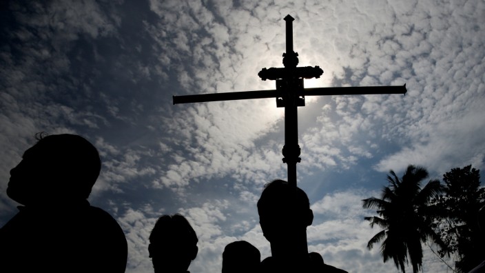 A man holds a cross during a mass burial of victims at a cemetery near St. Sebastian Church in Negombo