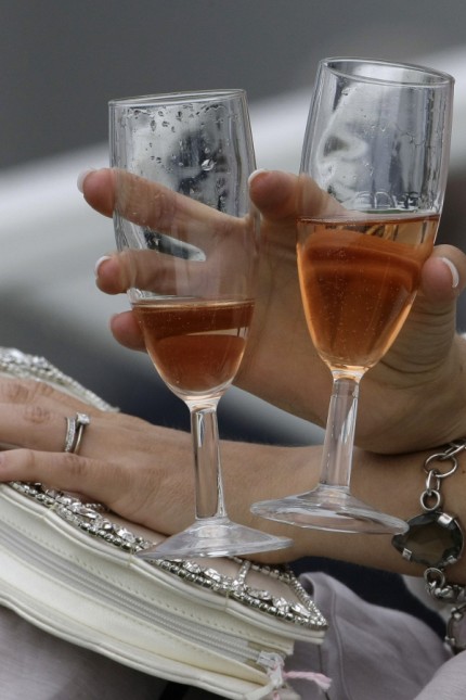 A woman holds champagne flutes before the start of the first race of the Epsom Derby Festival at Epsom Downs in Surrey